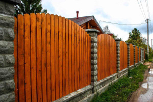 Секционный забор из деревянного штакетника с кирпичными столбами